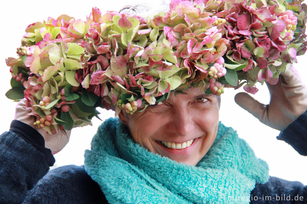 Detailansicht von Die Gärtnerin Ulrike Hager mit Blumenkranz aus Bauernhortensien und Schneebeere
 