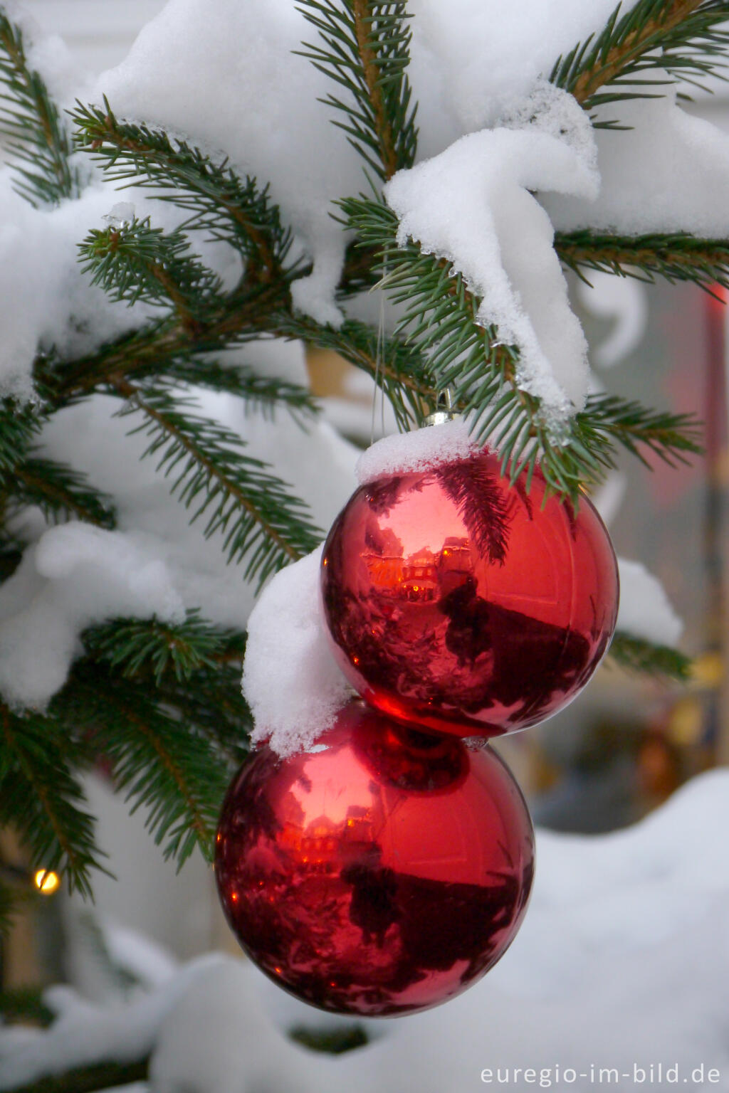 Weihnachtskugeln an verschneitem Tannenbaum
